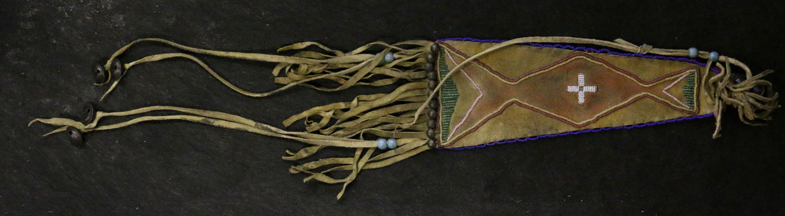 Beaded Ornamental Drop: Beaded Ornamental Drop with geometric motif with fringe and 6 Hawk Bells, 23" long, sinew-sewn.