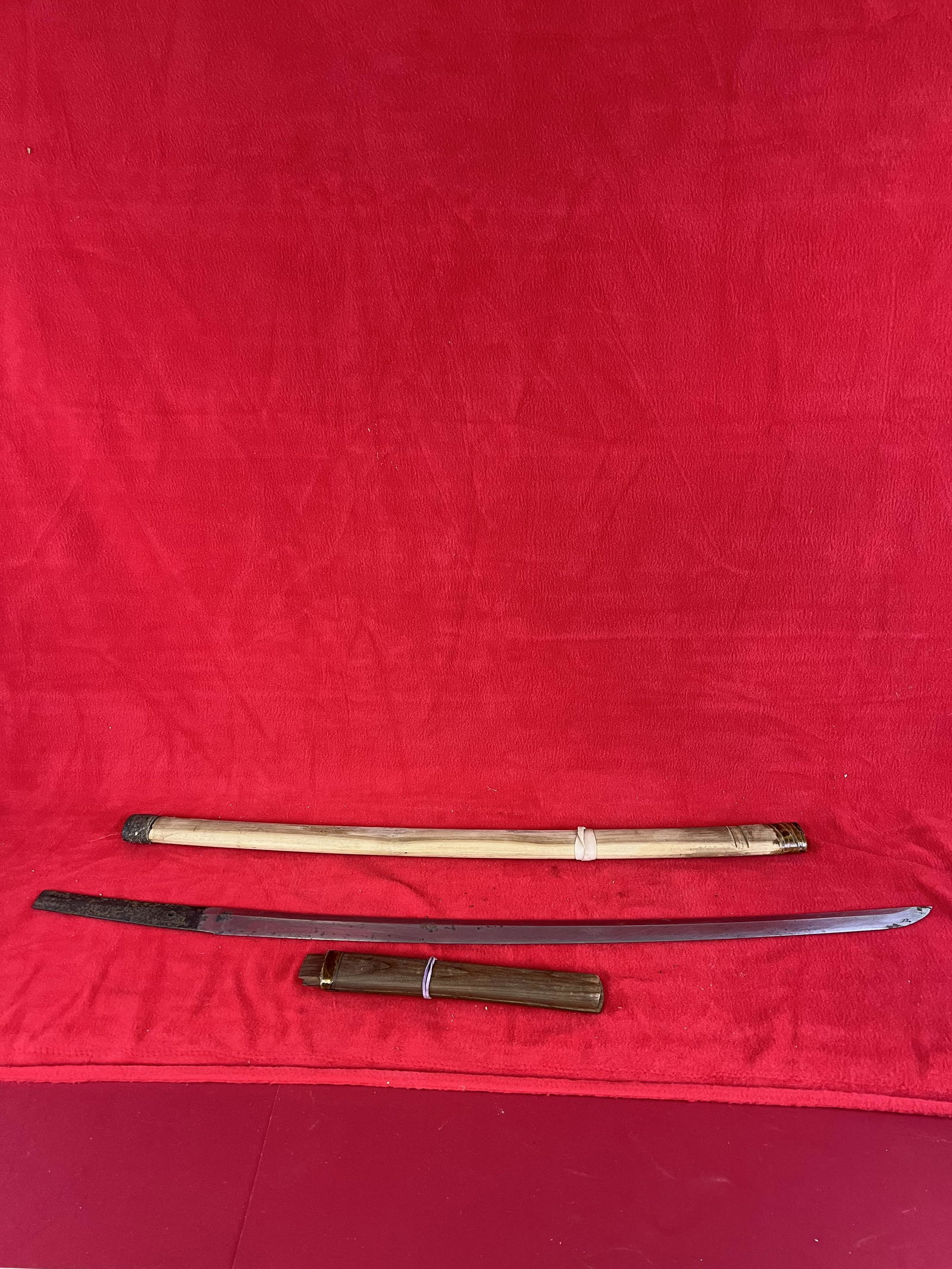 Japanese Samurai Sword: Japanese Samurai Sword in wooden case. The blade measures approximately 27 1/2" long and appears to be unsigned. Blade evidences some sharpening scratches and a couple small spots of surface rust.