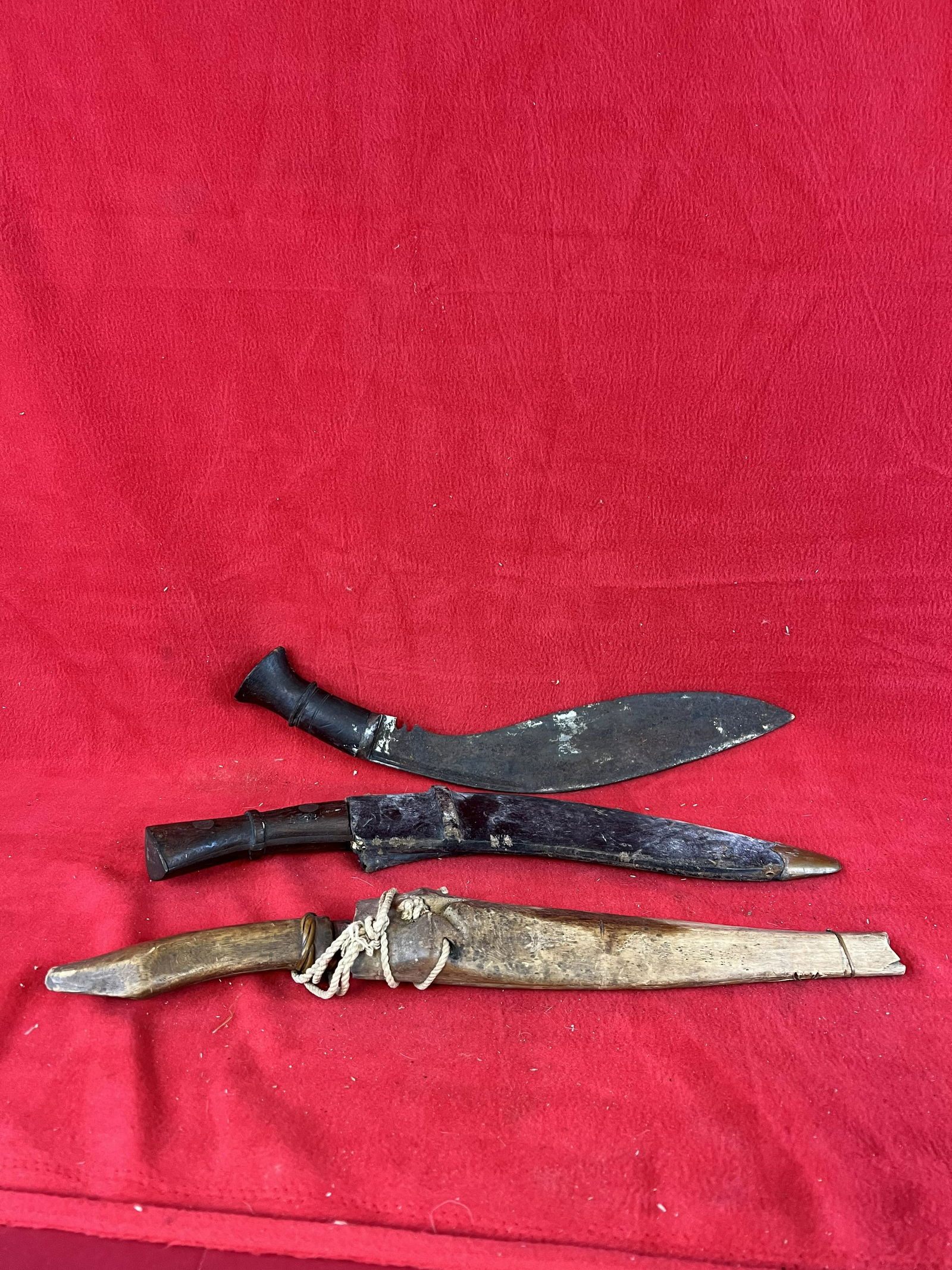 Lot of Three Gurkha Daggers: Lot of Three Gurkha Daggers two of which have sheaths on of carved wood the other wood covered in hide. The daggers have carved wooden handles and heavy metal blades. Condition - is as shown with some