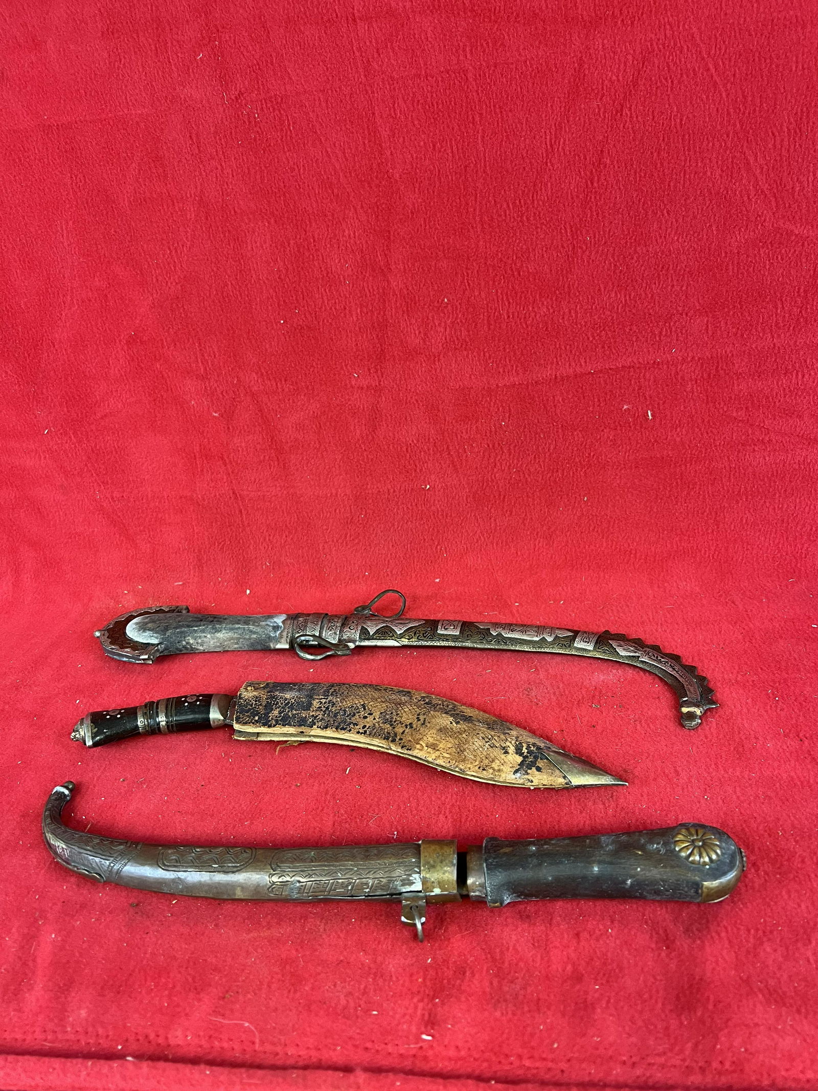 Lot of three Turkish Dagger: Lot of three Turkish Daggers one of which is Gurkha shaped with a inlaid horn handle and a leather covered wooden sheath. The other two are with curved pointed tips one housed in a ornate brass sheath