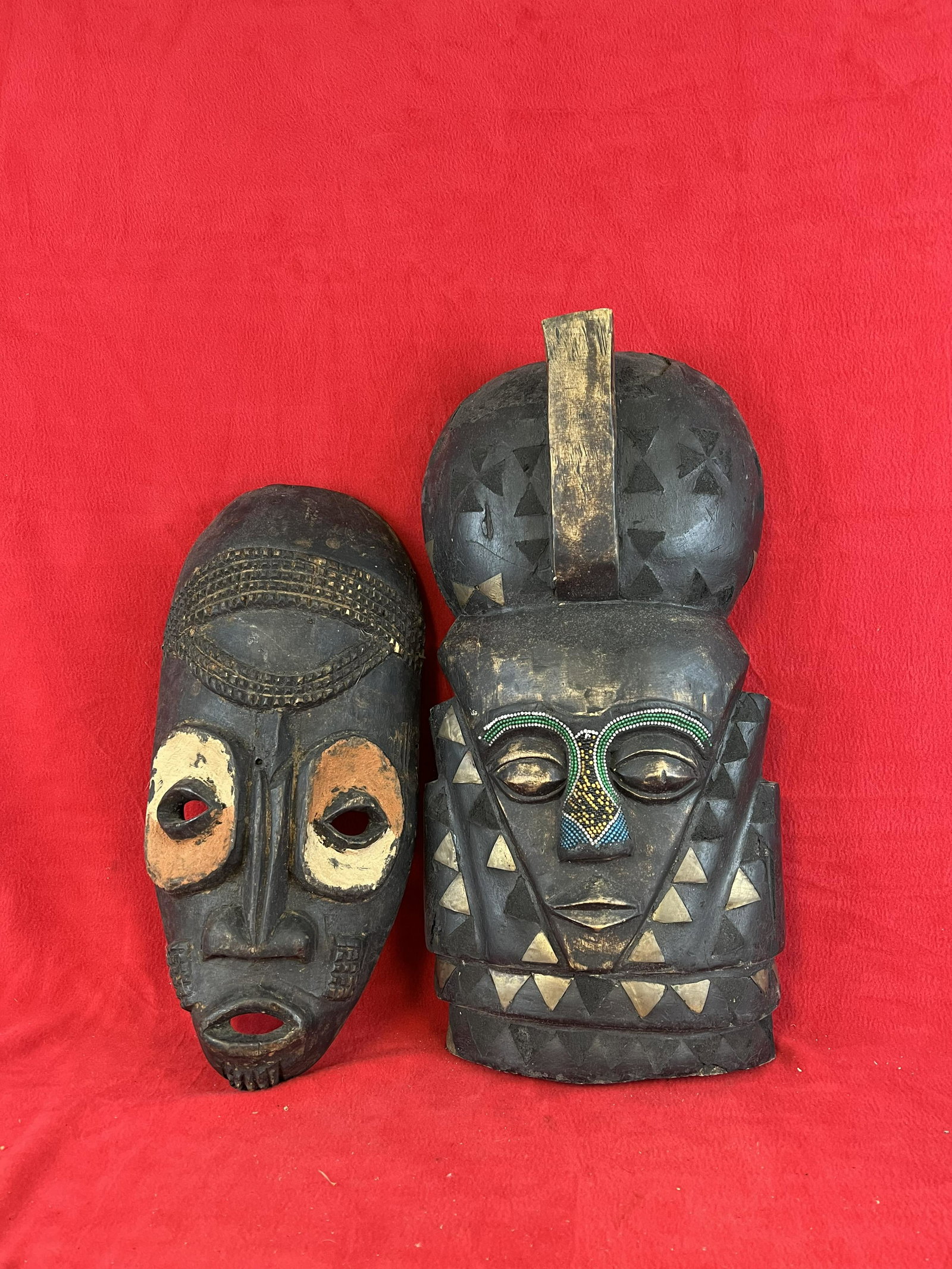 Lot of Two Hand Carved African Masks: Lot of Two Hand Carved African Masks one of which has painted decoration while the other has multicolored glass bead work and metal inlay. The tallest mask measures approximately 22 1/2" tall. Conditi