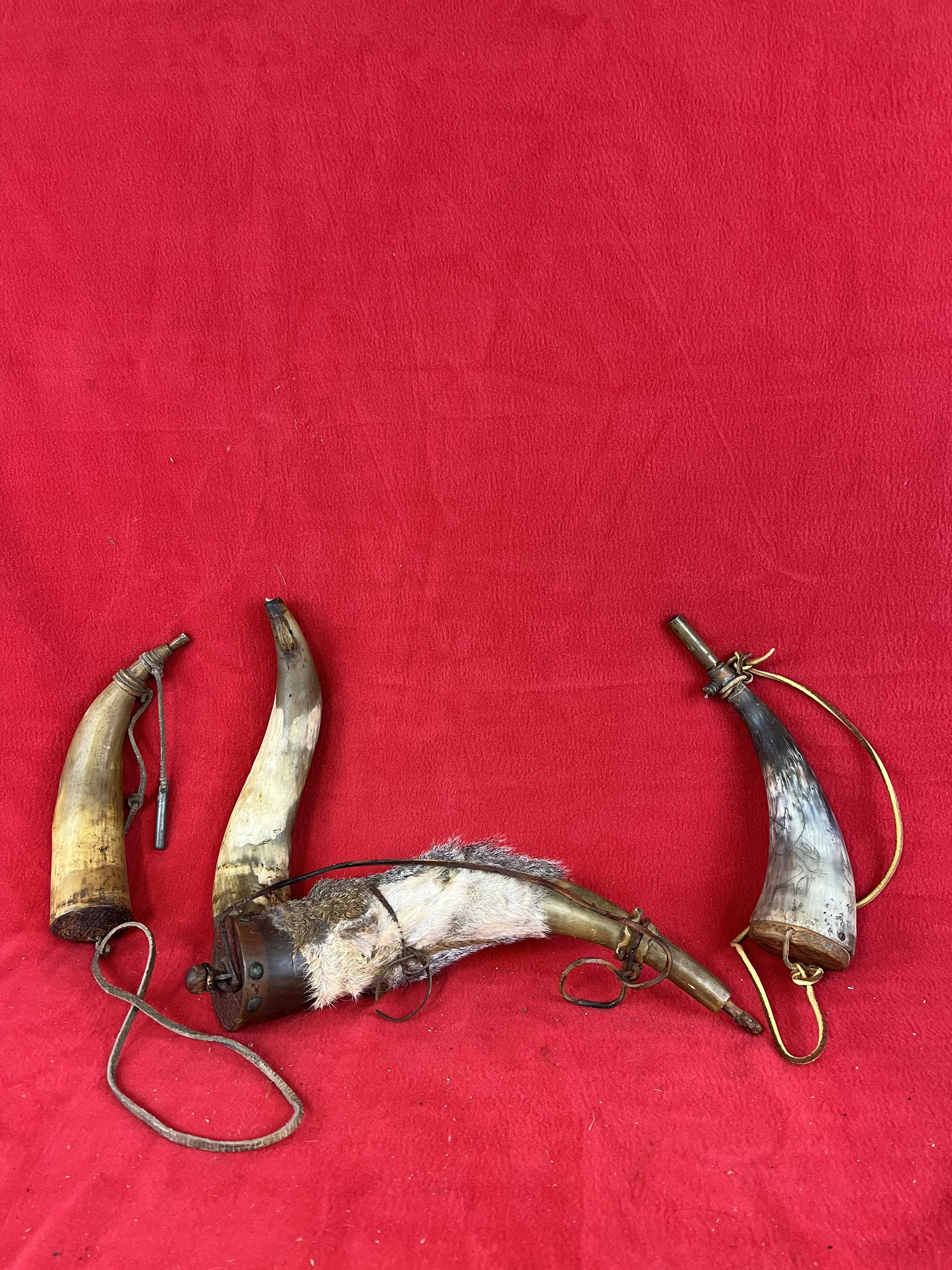 Lot of Four Antique Powder Horns: Lot of Four Antique Powder Horns one of which is fur covered and another which has a brass spout and is engraved with depictions of deer. The largest powder horn measures approximately 13" not includi