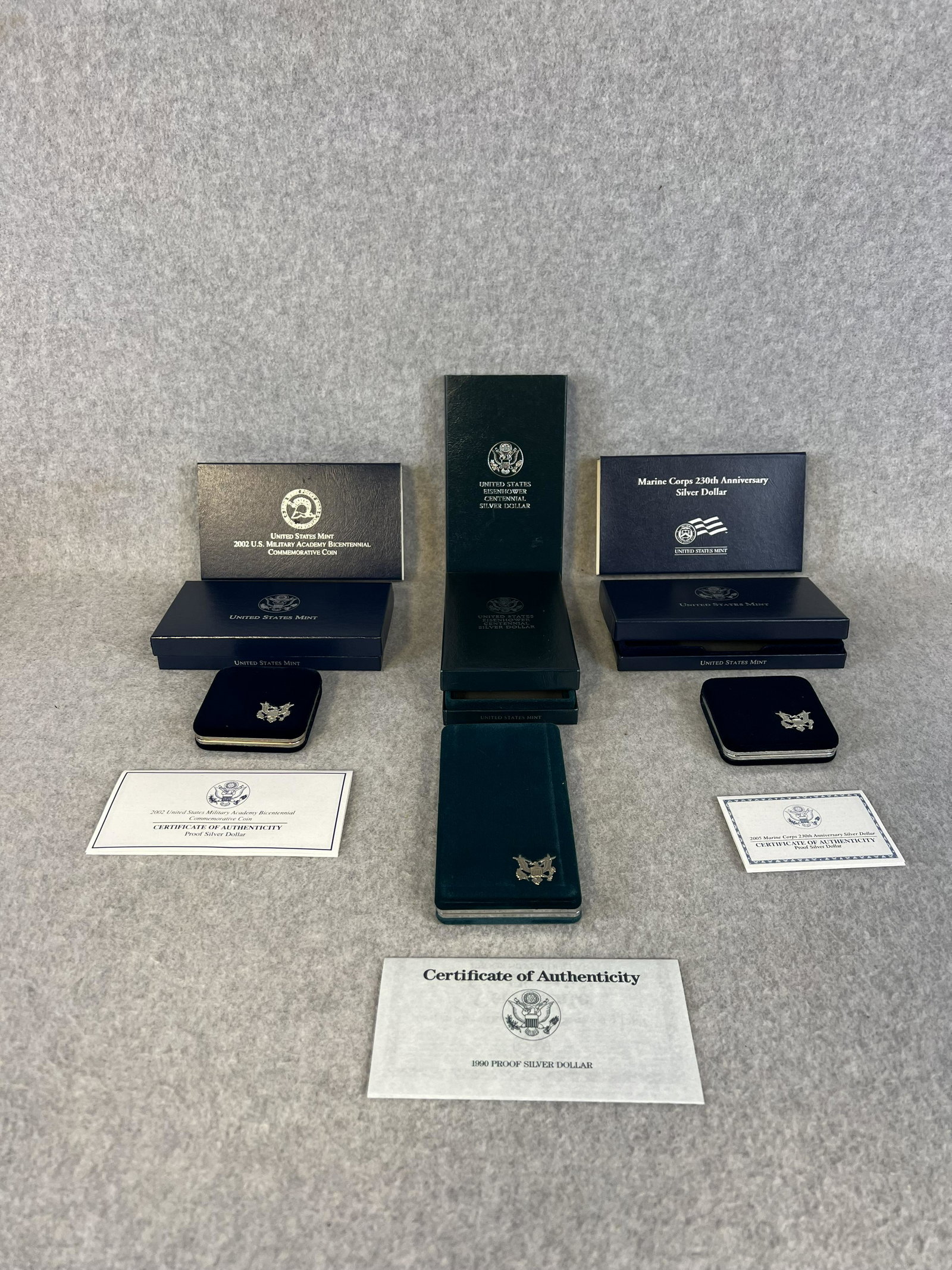 Lot 3 US Mint Coin Sets; 1990 Eisenhower Proof Silver Dollar, 2005 Marine Corps 230th Anniversary: Lot of three US Mint commemorative coin sets to include a 1990 Eisenhower proof silver dollar, a 2005 Marine Corps 230th anniversary silver dollar and a 2002 U.S. Military Academy bicentennial commemo