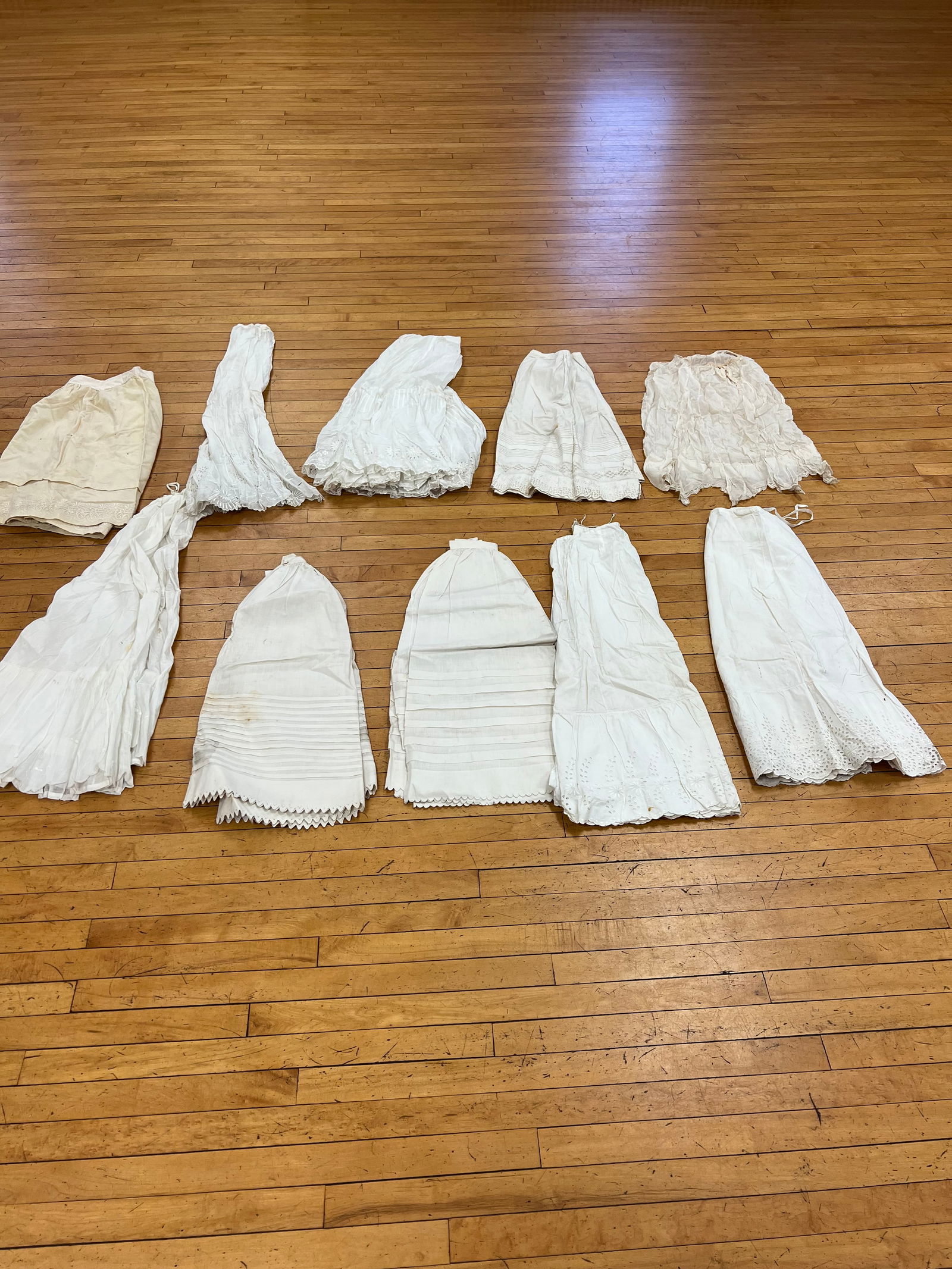 Lot of 9 Vintage White Linen Petticoats: Lot of 9 Vintage White Linen Petticoats, with cut work and applied decorations. There is various levels of staining that will require careful cleaning.