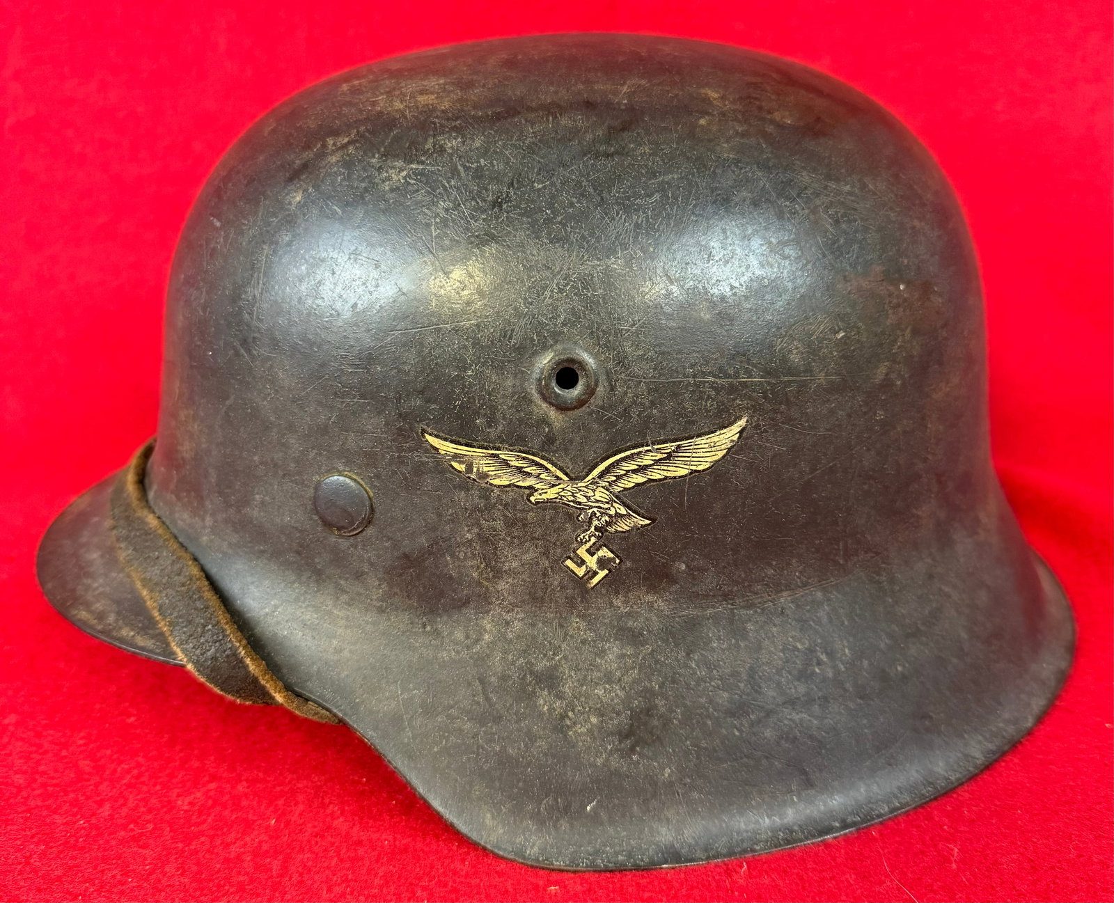 German Luftwaffe Model 35 Single Decal Helmet: World War Two German Luftwaffe Model 1935 single decal helmet with 80% of its dark blue-grey paint and with its original liner and having a chinstrap. Helmet retains about 90% of its Luftwaffe decal.