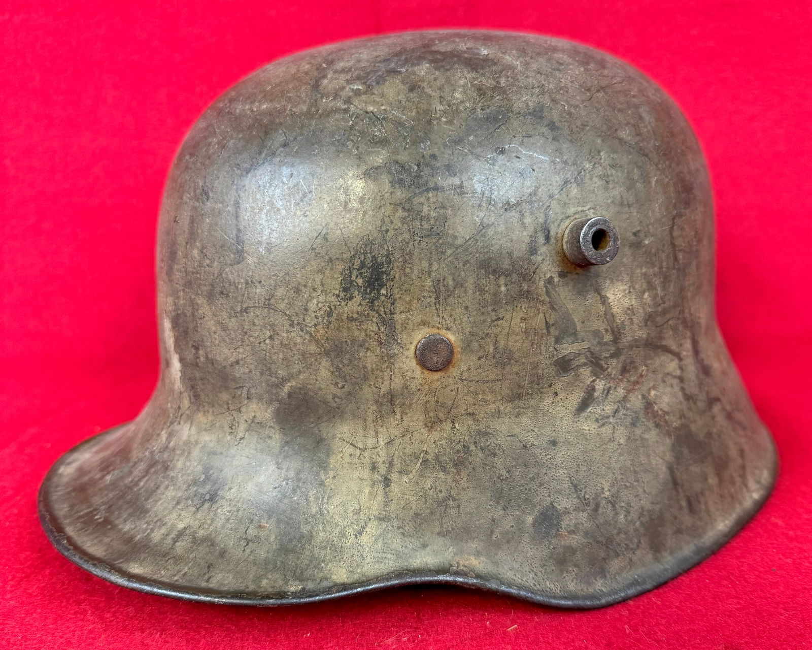 German WW1 Model 1916 Light Camouflage Helmet: German World War One Model 1916 helmet with gray olive camouflage paint. Helmet lacks liner and chinstrap and there is wear to its original surface.