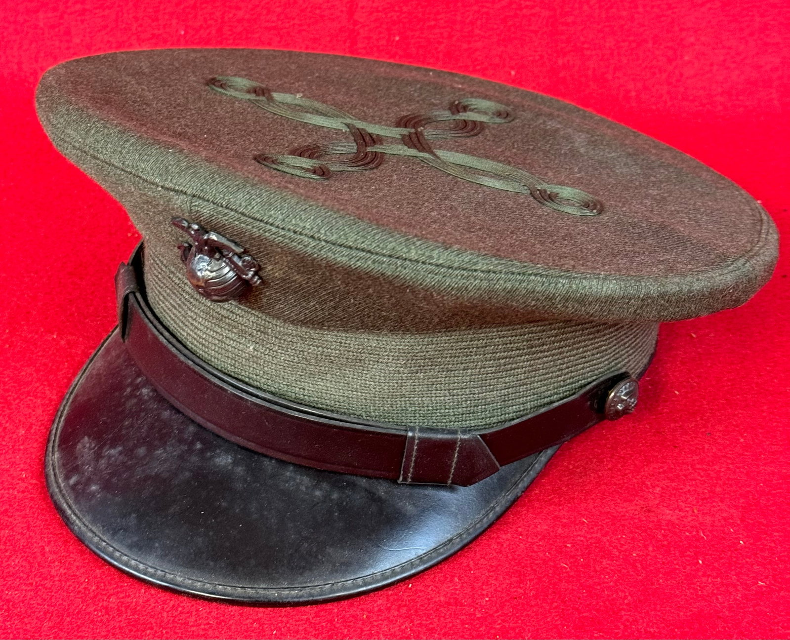 WW2 USMC Officer's Visor Cap: World War Two United States Marine Corps Officer's visor cap in dark green with black leather visor and having green taping on the crown in a quatrefoil pattern and was made by Berkshire Caps.The quat