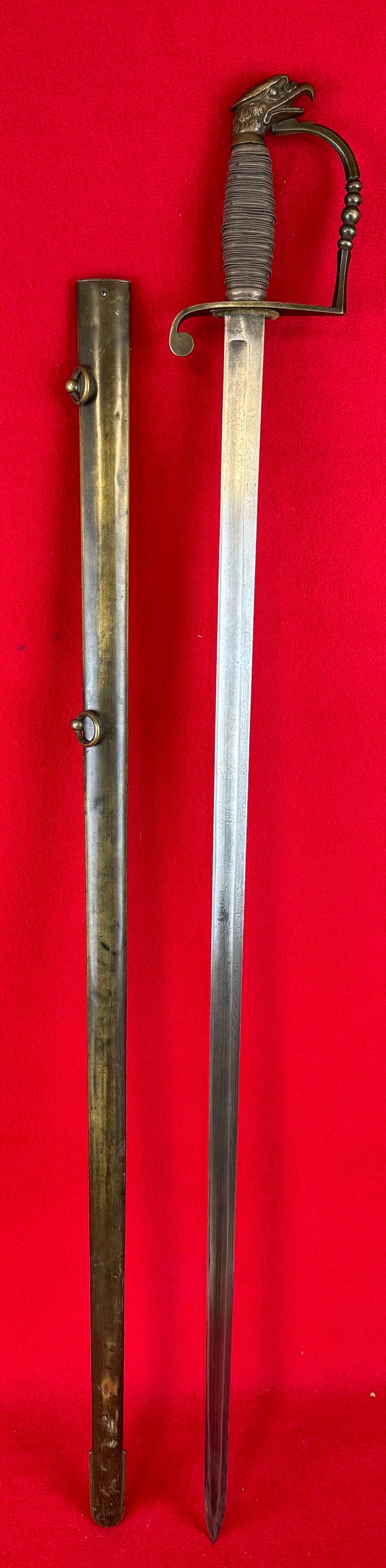 War 1812 Eagle Headed Sword With Silver Grip: US War Of 1812 eagle headed sword with silver wire wrapped grip and having a blade etched with military insignia and foliate motifs. Sword comes with its original scabbard having two carrying rings an