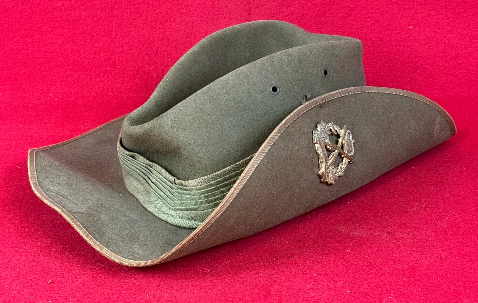 WW2 Australian Slouch Hat With Infantry Badge: World War Two Austrian Slouch hat of olive drab felt and cotton puggaree hat band with gilt metal Royal Corps Australian Infantry badge at side. Hat has a hole at back near crown otherwise fine.