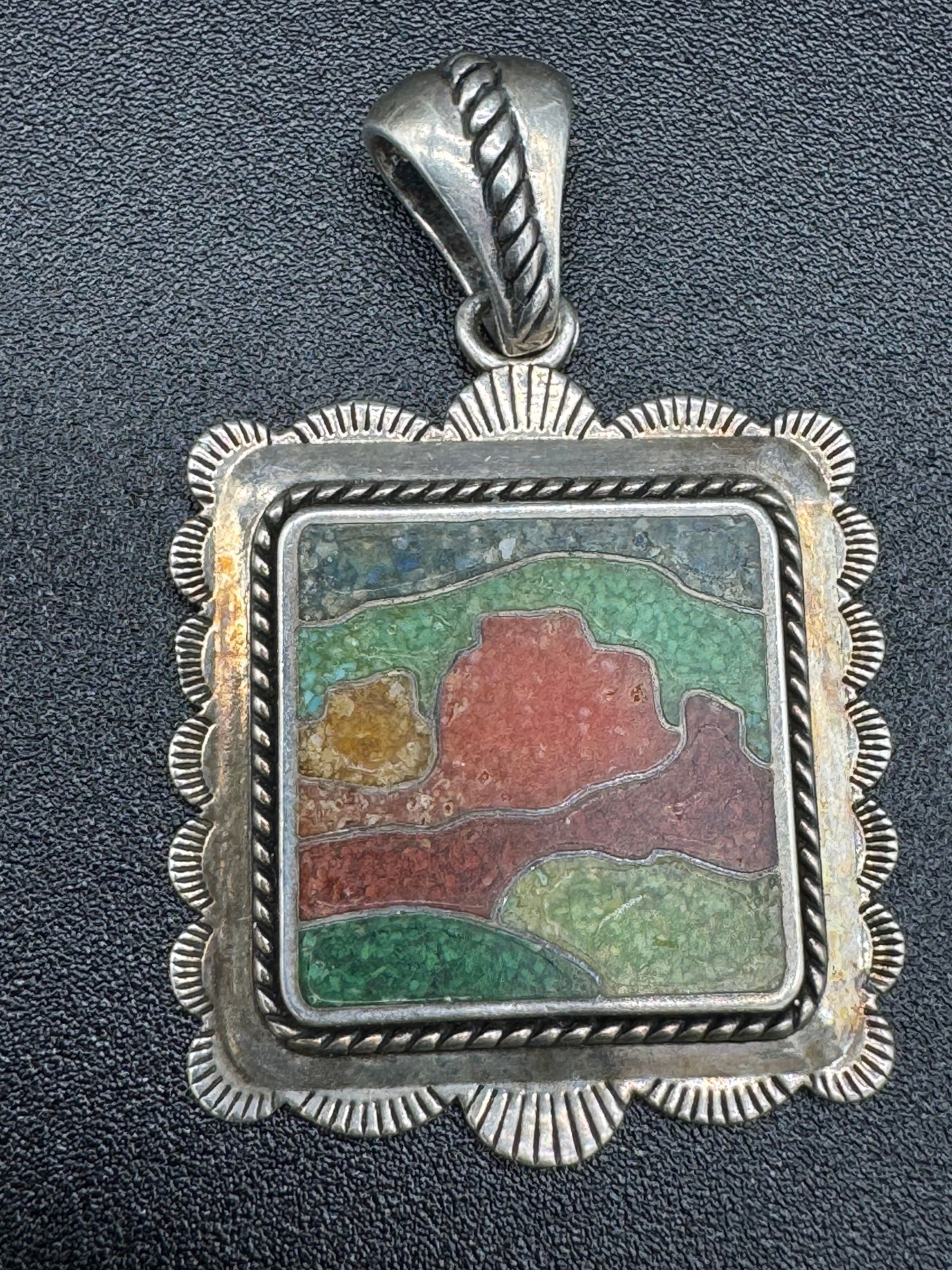Sterling Silver Inlaid Pendant: Vintage hand crafted sterling silver pendant the front of which has various colored inlays with silver wire borders. Pendant measures approximately 1 1/4" square not including top loop and the weight