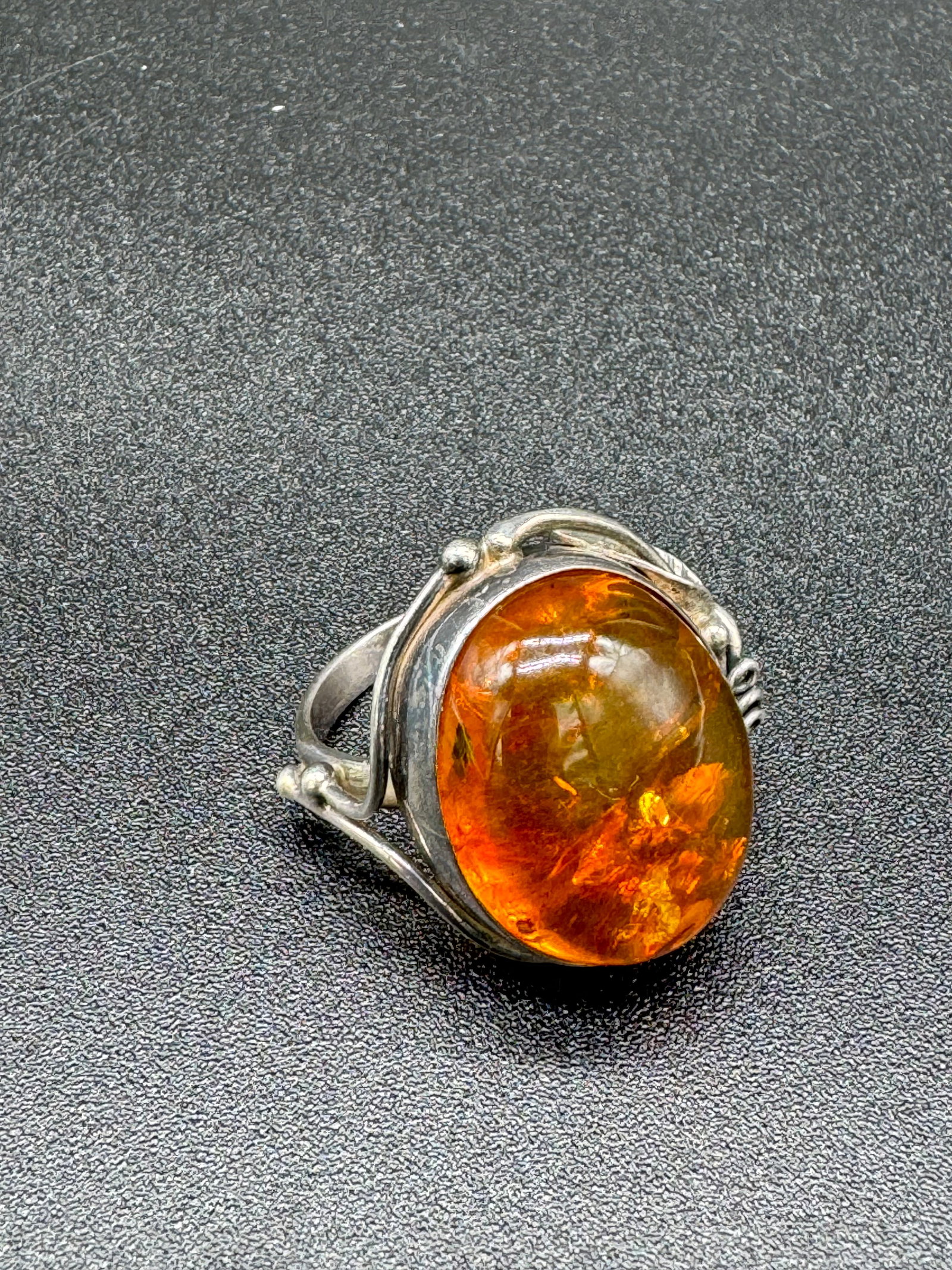 Sterling Silver & Amber Ring: Vintage sterling silver ring set with amber at front. The ring has a leaf decoration at the edge and the ring size is a 9 1/4 and the weight is .38ozt. Condition - excellent.