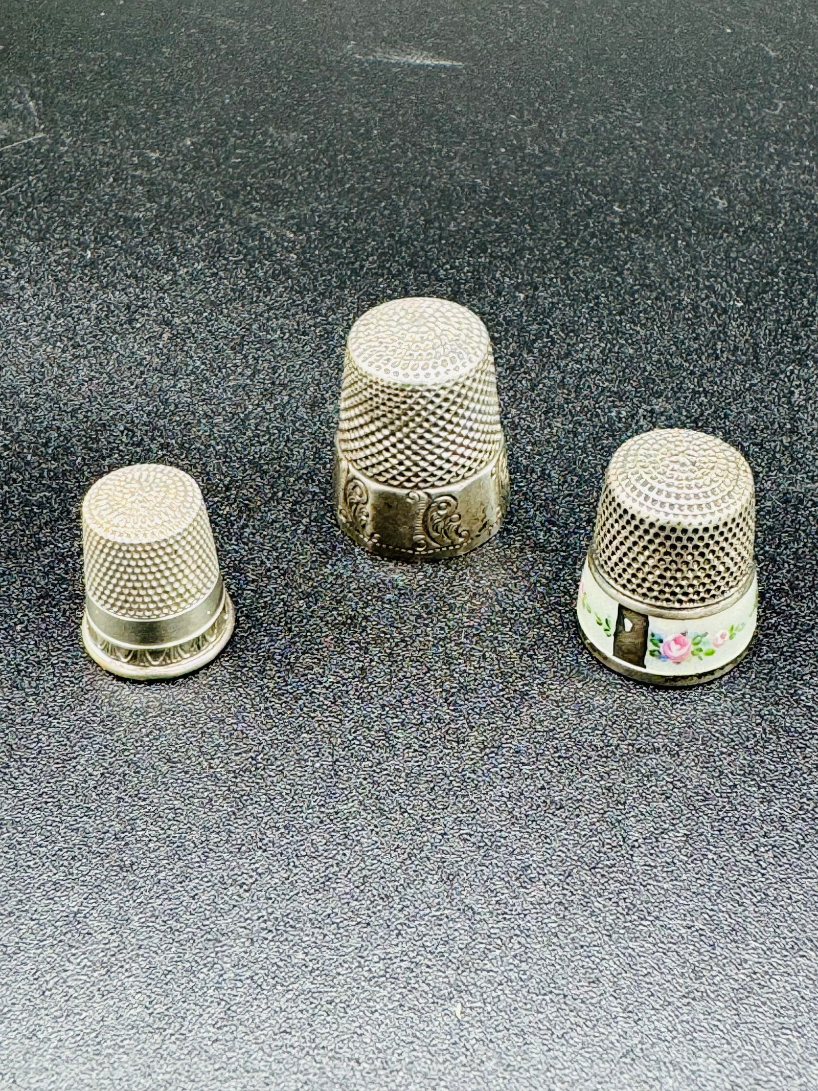 Lot 3 Antique Sterling Silver Thimbles: Lot of three antique sterling silver thimbles one of which is decorated with enamel. The largest thimble which is a size 11 has panel sides to its apron and is marked by the maker on the interior of t