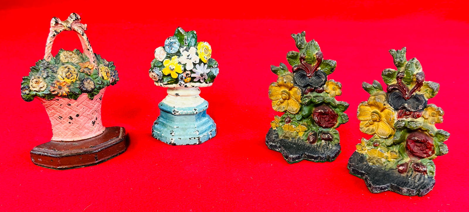 Antique Painted Cast Iron Doorstops & Bookends: Lot consisting of antique painted cast iron doorstops and a pair of bookends. Doorstops are in the form of a basket of flowers and a flower filled urn while the pair of bookends are in the form off fl
