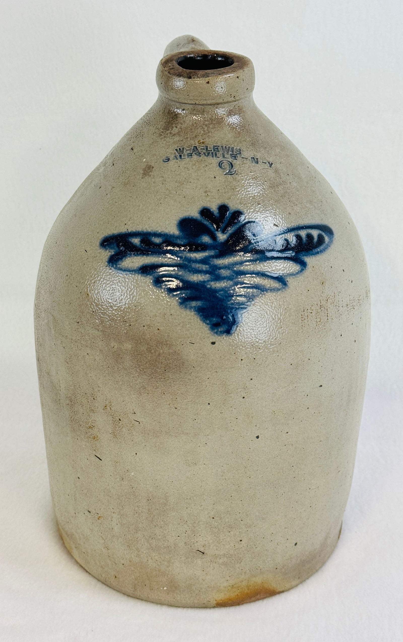 William A. Lewis Galesville N.Y. Jug W Bl Floral: 2 gallon straight sided jug stamped W A Lewis / Galesville NY with a blue floral decoration. Jug measures approximately 13 1/4" tall. Condition - generally excellent with one approximately 3" extremel