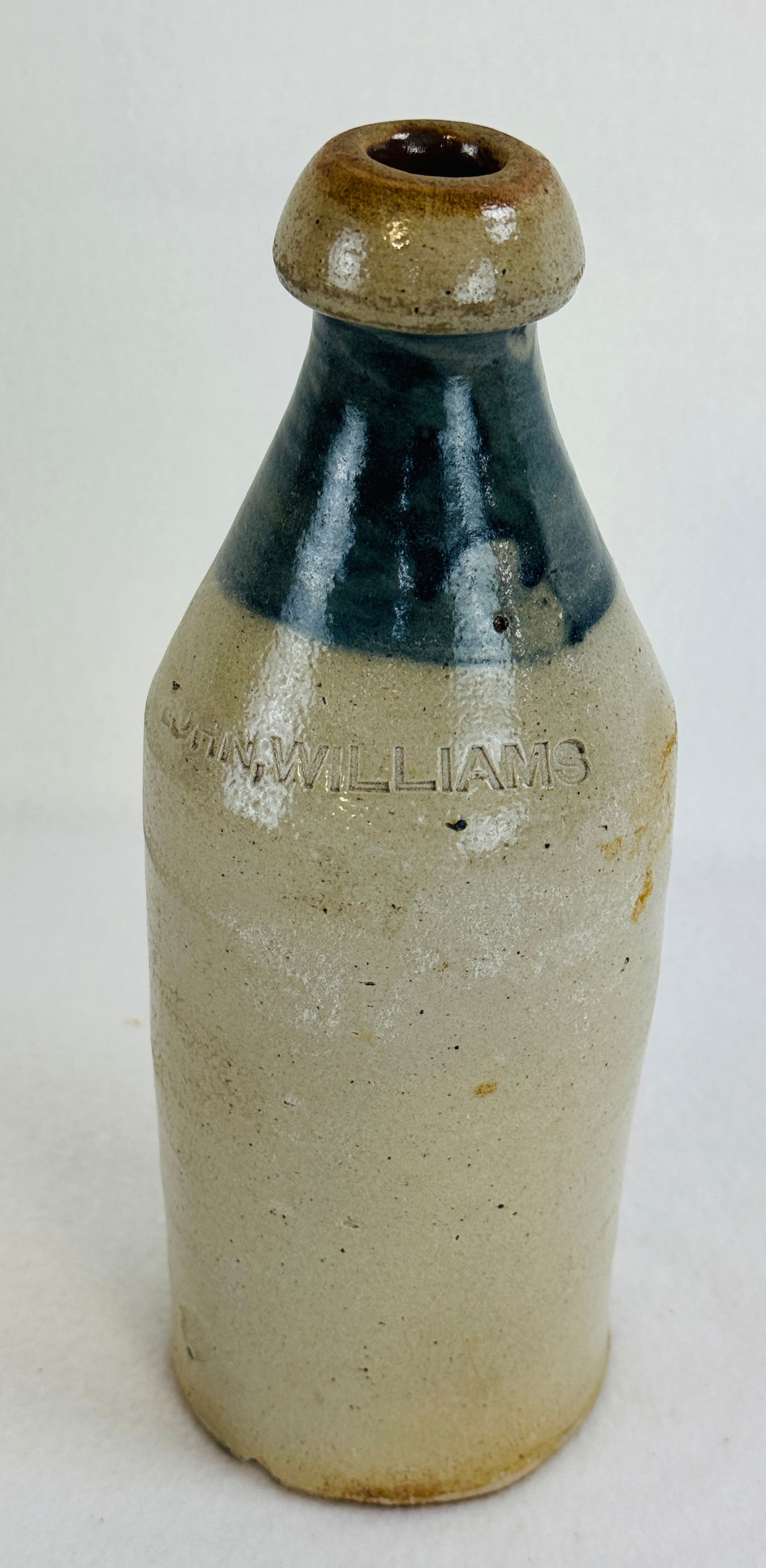 10 1/4" John Williams Stoneware Bottle: 10 1/4" stoneware bottle impressed at shoulder John Williams and having a cobalt band. Condition - one small chip beneath base otherwise excellent.