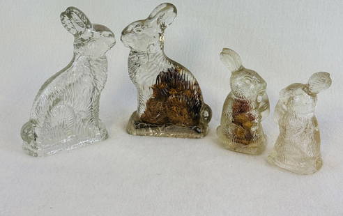 Lot 4 Rabbit Form Candy Containers: Lot of four clear molded glass candy containers in the form of rabbits two of which have their original candy contents and heavy cardboard closures. The larger size container measures approximately 6