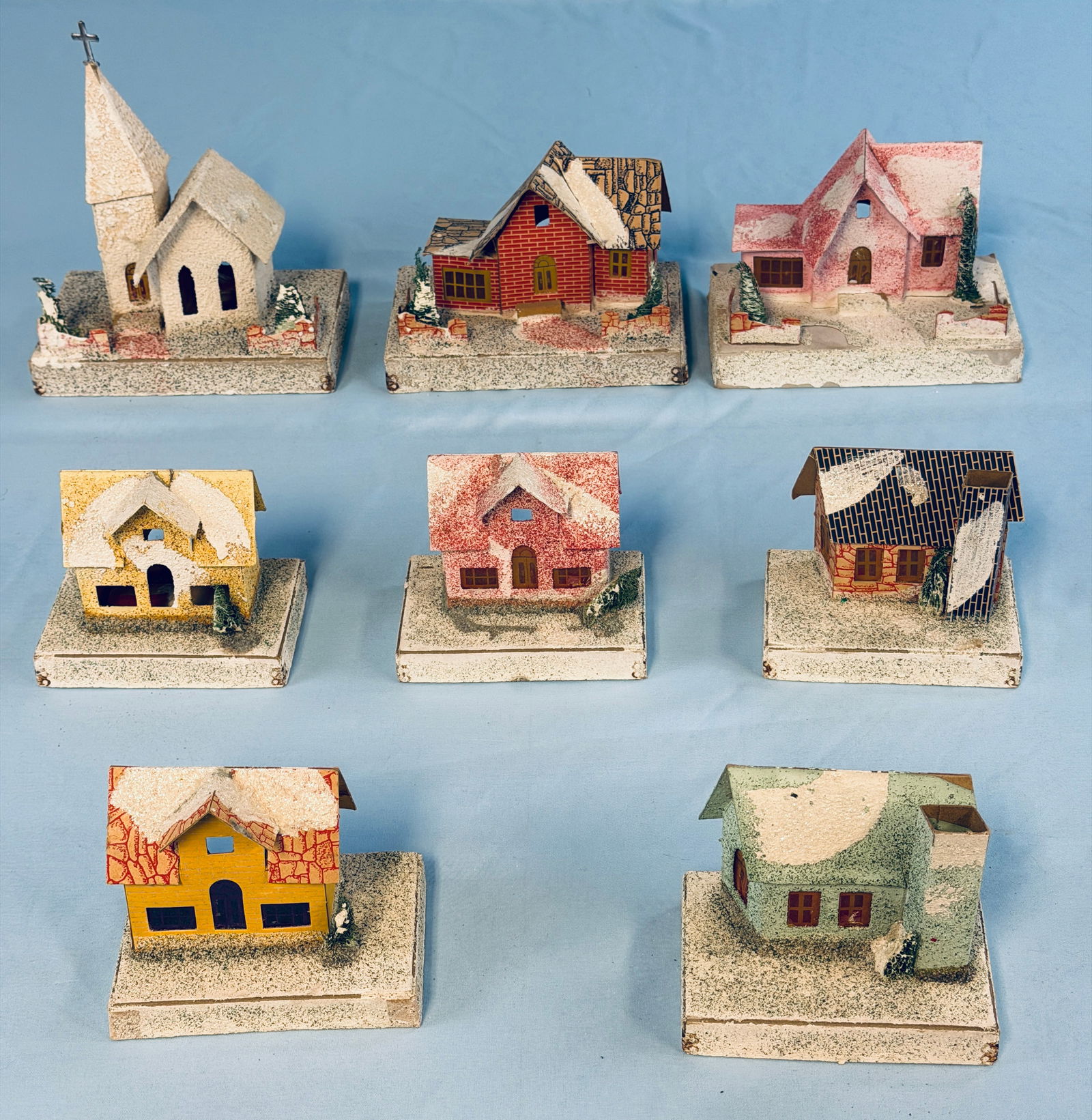 Lot 8 Vintage Putz Christmas Buildings: Lot of eight vintage putz Christmas buildings the tallest of which (Church) 7 3/4" is marked on the underside of the base The Dolly Toy Co USA. Condition - some flaking to paint on base of one and som