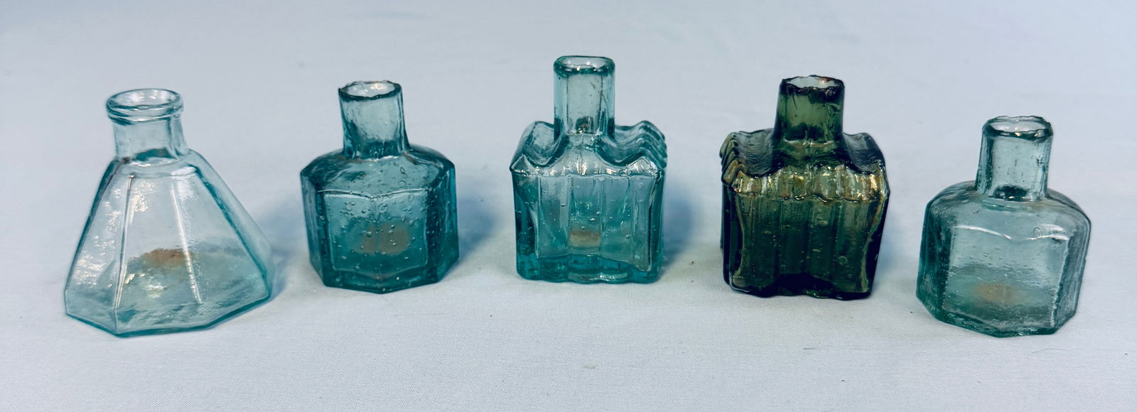 Lot 5 Ink Bottles Included OP Umbrella: Lot of five antique ink bottles which includes a aquamarine eight sided open pontil marked umbrella ink along with four various color English smooth base blow top inks. Condition - all appear to be in