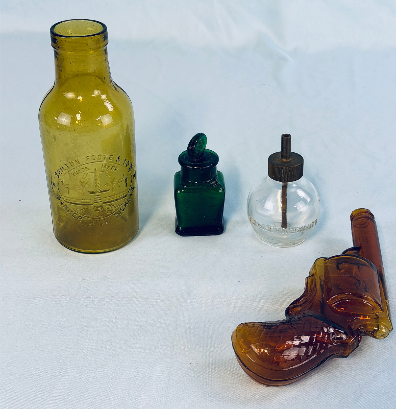 Lot 4 Misc Antique Bottles: Lot of four antique bottles to include a 7 3/4" honey amber Bunker Hill Pickles, a emerald green Larkin Soap Co bottle with stopper (stopper stuck in place as typical), a amber pistol figural bottle i