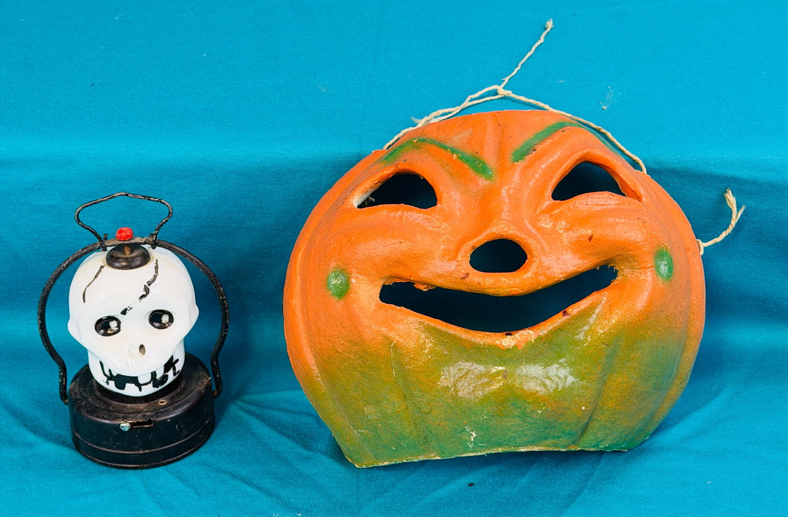 Vintage Halloween Lot Mask & Electric Lantern: Lot of vintage Halloween items to include a pulp pumpkin mask made from a lantern together with a Hilco figural cast milk glass electric lantern in the form of a skull with tin battery compartment. Co