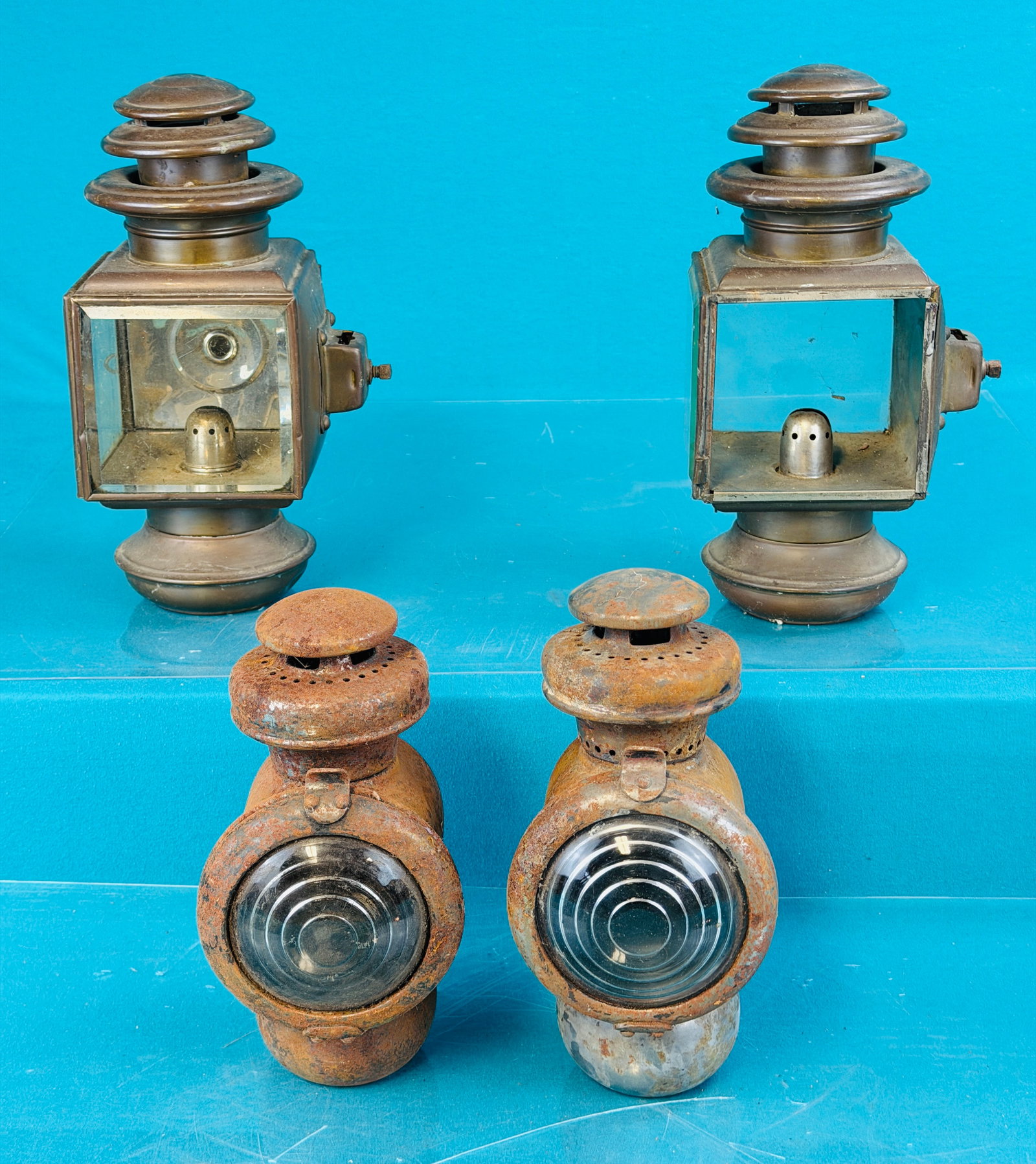 Lot 4 Antique Automobile Lamps: Lot of four early kerosene automobile or carriage lamps which include two set the one set is made of brass and one lacks its front door with beveled glass. The second set has surface rust to each but 