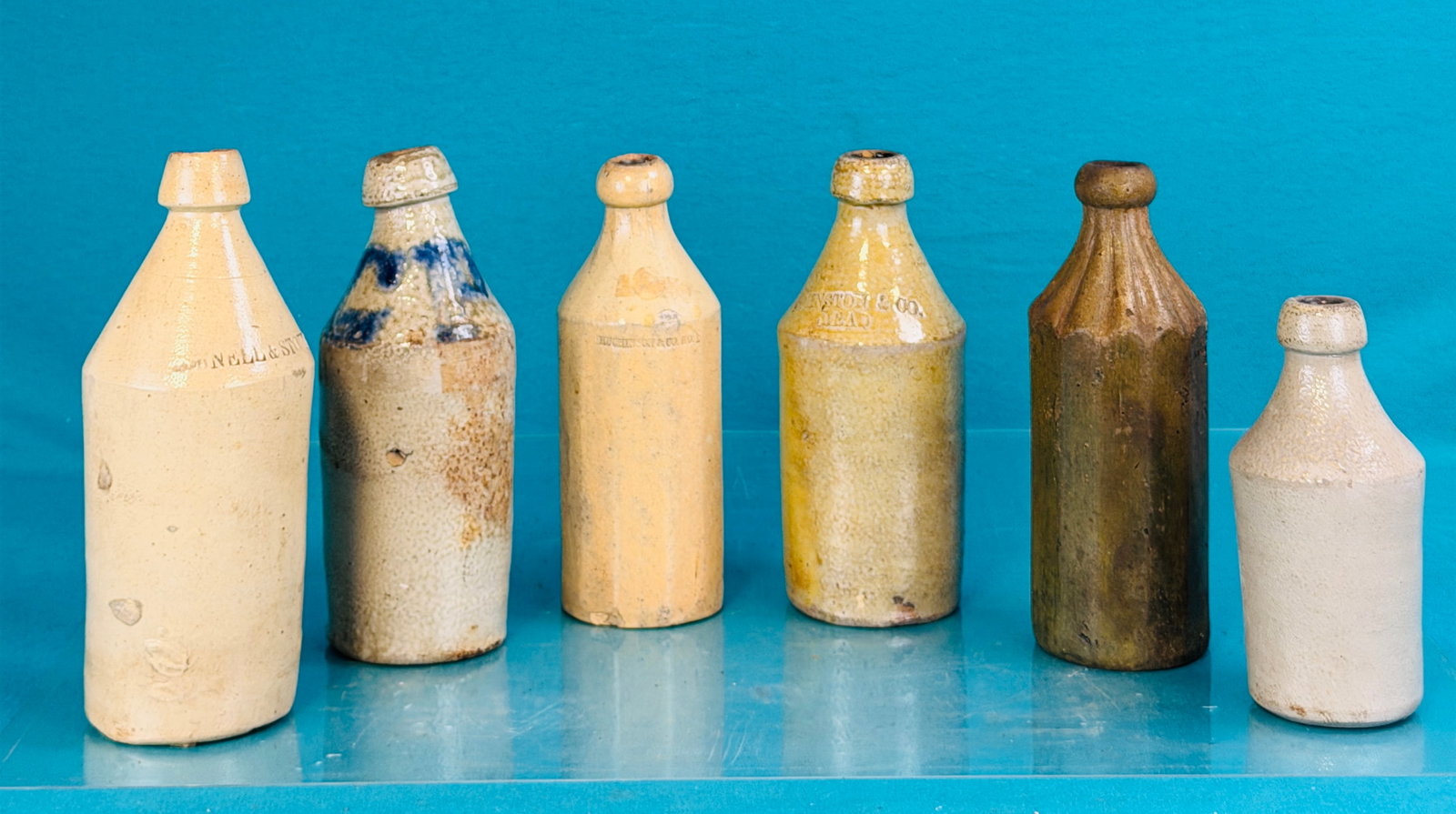 Lot 6 19th C Stoneware Bottles: Lot of six 19th century stoneware bottles five of which are quarts with the other being a pint. The quarts are all debossed with a retailers name and one has the cobalt initials CP at the shoulder. Th