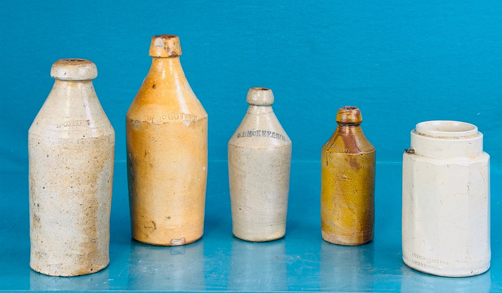 Lot Stoneware Including Bottles: Lot of four 19th century stoneware bottles two of which are quarts and all are debossed with a retailers name together with a paneled stoneware jar Lutz & Schramm Co made by the Sherwood Bros. Pottery