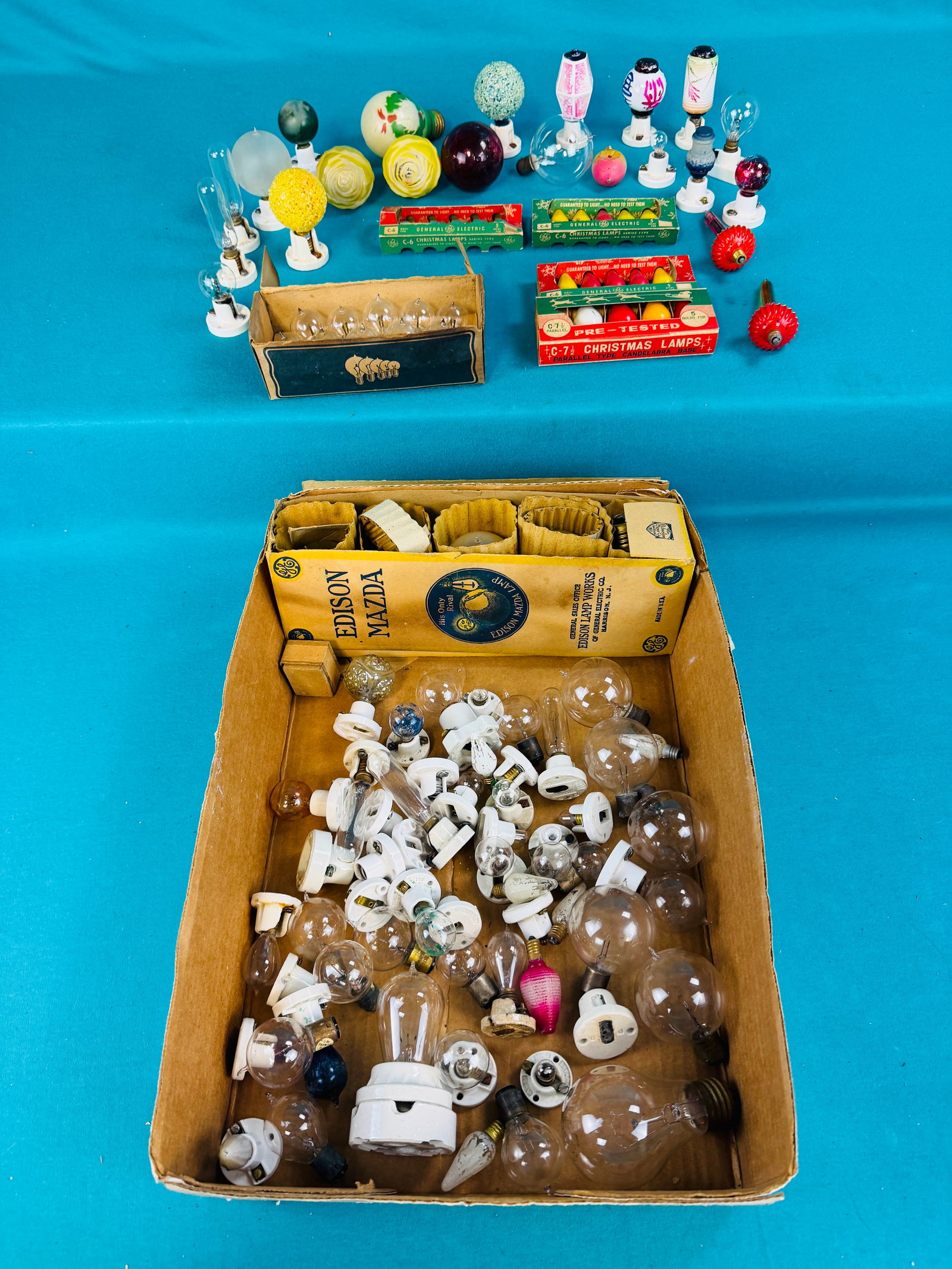 Lot Early Light Bulbs Including Christmas Etc: Large lot of early light bulbs many with exhaust tips along with many early white porcelain sockets. Lot includes some figural Christmas bulbs as well as some sets in their original packaging. Conditi