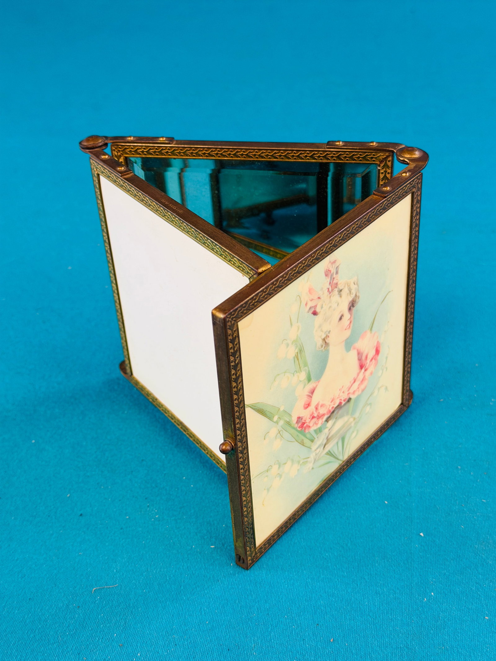 Ornate Victorian Three Part Dresser Mirror: Victorian late 19th century three part womans dresser mirror. Item has a brass frame and folds so that the top panel which is celluloid and features a beatiful woman is shown. Mirrors are bevelled gla