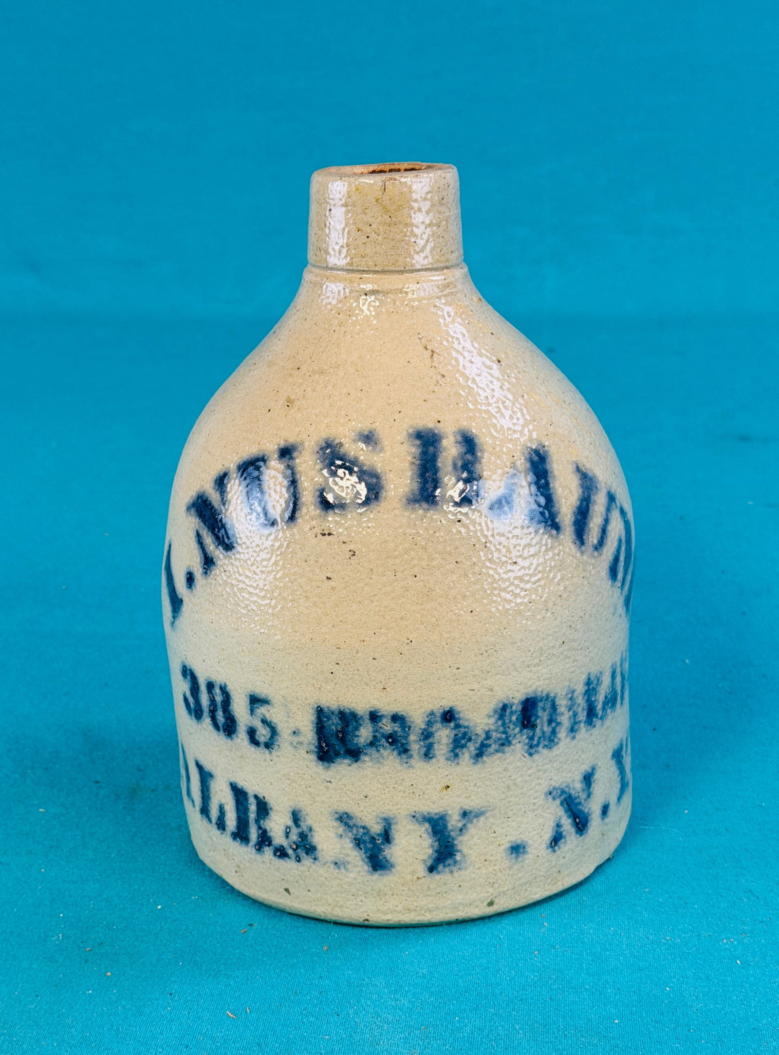 I. Nusbaum Albany Stoneware Advertising Jug: Antique one gallon size salt glazed stoneware advertising jug which is stenciled for I. Nusbaum 385 Broadway Albany N.Y.. Jug stands approximately 9 1/2" tall. Condition - small shallow flake to the t
