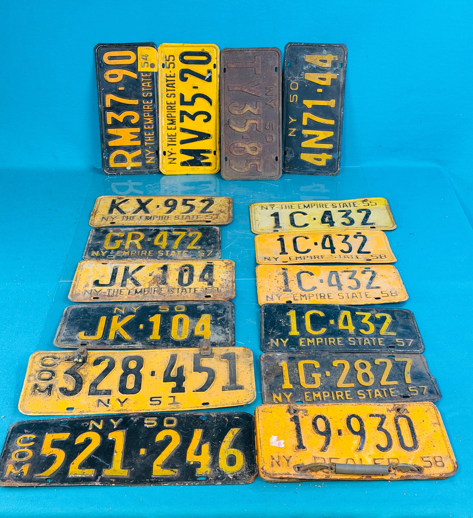 Lot 17 1950's NYS License Plates Incl PR Dealer: Lot of seventeen 1950's New York State license plates which includes a pair of 1958 dealer plates held together with spring clamps with brass ends marked Auto Aides. Condition - is as shown. In house 