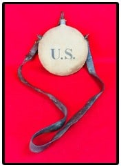 U.S. Spanish American War Canteen w RIA Strap: United States marked Spanish American War era canteen with original cloth covering marked U.S. and having a period marked R.I.A. (Rock Island Arsenal) leather shoulder carry strap. Canteen is in very 