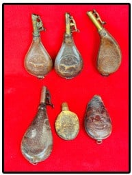 Lot 6 Antique Leather Shot Flasks: Lot of six leather shot flasks four of which are fitted with brass spring loaded chargers one of which is marked by James Dixon & Sons Sheffield. Three flasks have embossed scenes two depicting a hunt