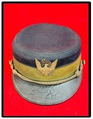 US Military Cap With Embroidered Eagle Insignia: Antique military cap made and marked by the M. C. Lilley & Co Columbus Ohio which has a black leather visor and has a embroidered eagle insignia at front. Condition - has some minor wear and soil as s