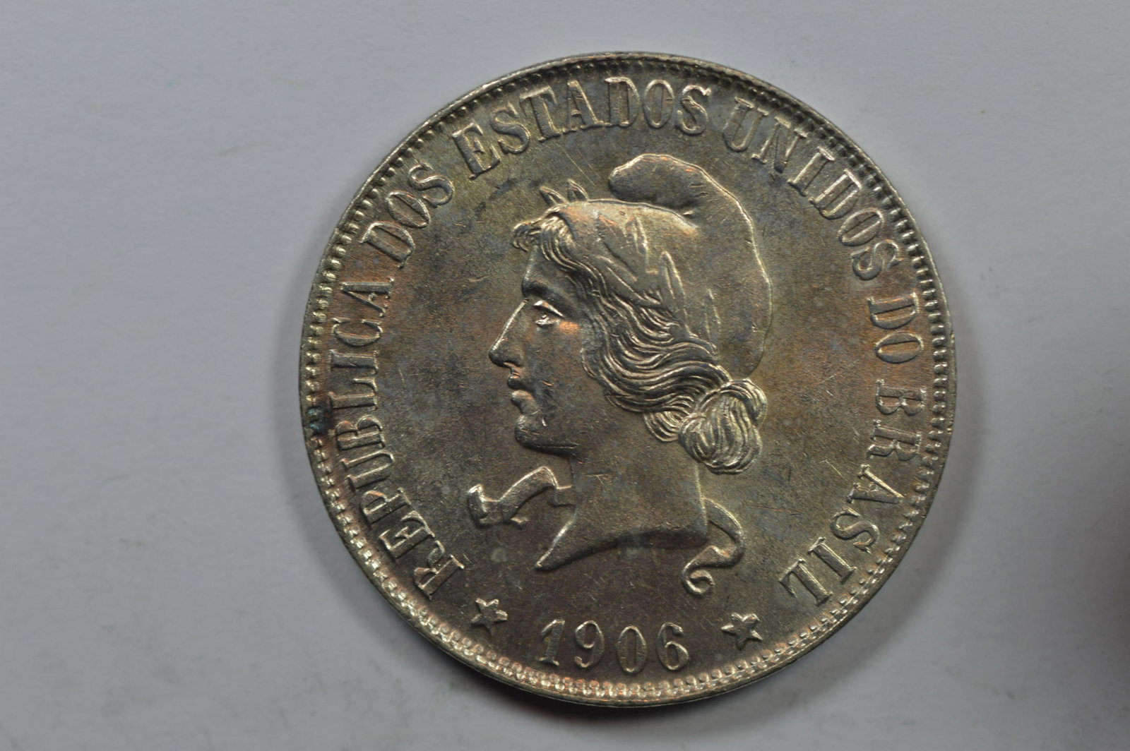 Brazil 1906 Silver 2000 Reis (KM-508, .5787 oa ASW): Brazil 1906 Silver 2000 Reis (KM-508, .5787 oa ASW). BU and virtually worthy of a fully Choice distinction. The surfaces are assertive, balanced, and fully frosty. This scarce date is both a first yea