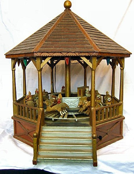 Large folk tramp art carousel with carved animal : Large folk tramp art carousel with carved animal figures mounted with miniature bisque doll figurines on moving turntable. Measures 28" high, 23" wide and 28.5". Has 14 animals with riders, strung lig