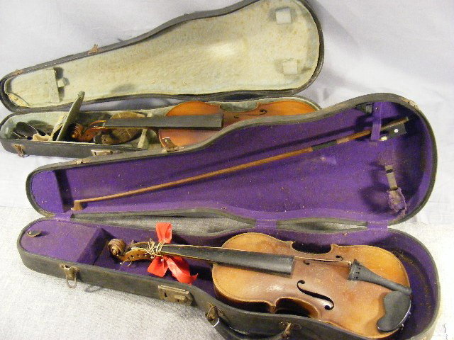2 Antonius Stradivarius violins, both missing pie: 2 Antonius Stradivarius violins, both missing piece at ends of finger boards, missing string pegs (only 3 in lot). Worn finish. 1 bow, both have cases.