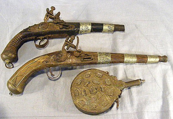 2 antique Arabian flintlock pistols w/ flask. Pis: 2 antique Arabian flintlock pistols w/ flask. Pistols are damaged, working mechanisms, sold as is. Longest is 17"