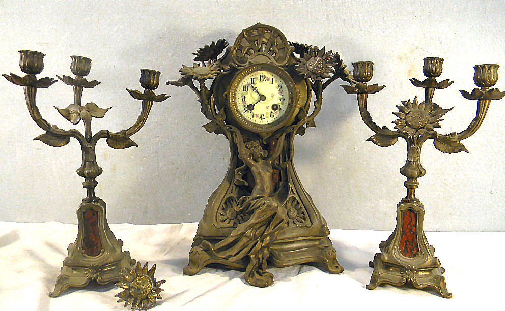 Art nouveau spelter clock and candelabra garnitur: Three piece art nouveau spelter clock and candelabra garniture set with marble inserts in base, no finish on spelter, one candelabra has repair and flower broken off, one petal missing, Clock movement
