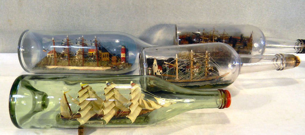 Four folk art sailing ships in bottles, each bottle 11.: Four folk art sailing ships in bottles, each bottle 11.5" long, three bottles with town scenes in background, each in very good condition