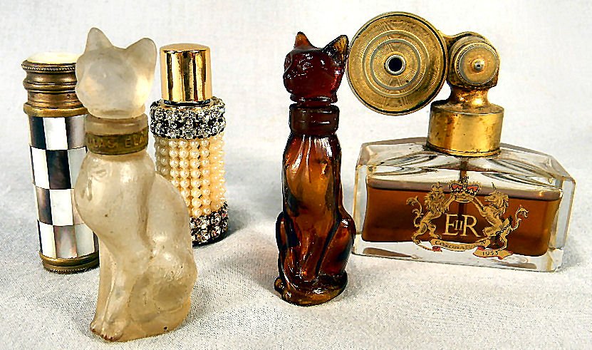 Lot of five perfume bottles, amber cat bottle with: Lot of five perfume bottles, amber cat bottle with label on bottom, clear cat bottle with Lilas Blanc on collar, pump atomizer unmarked with shell overlay, beaded bottle all with no chips or cracks an