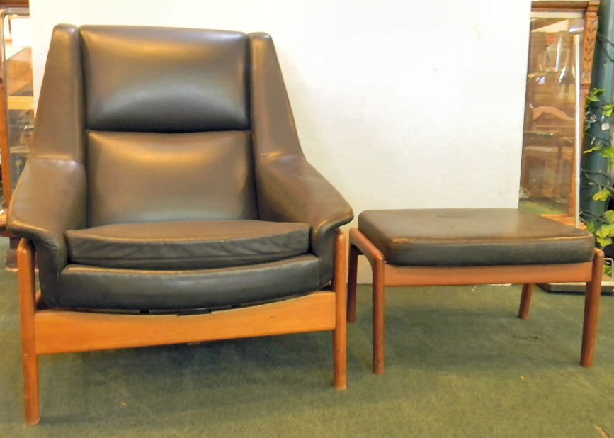Black leather upholstered modern styled platform rocker: Black leather upholstered modern styled platform rocker with adjustable ottoman, tagged "Illums Bolighus, Kobenhavn". Chair measures 34" wide, 24" deep and 37" high, light cracking to leather on foots