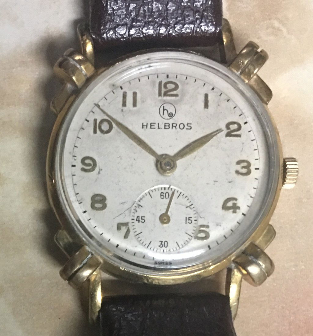Swiss Antique Helbros hand winding wristwatch 1960s: This handsome and rare 1960s Helbros wristwatch features a golden-tone case with a brown leather strap and a stainless steel back, as well as Mechanical of Swiss.