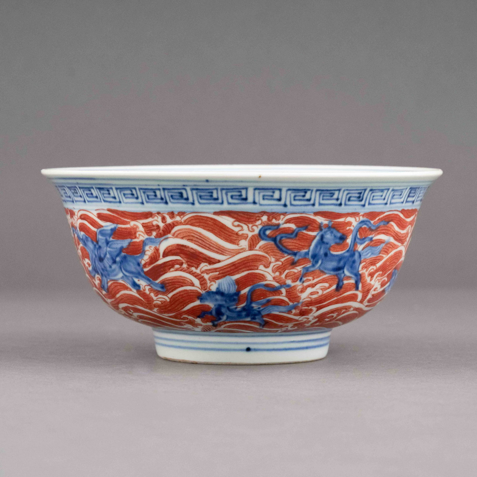 MING BLUE AND RED BOWL: Chinese Ming Dynasty Period, blue and red porcelain bowl. The porcelain potted with a shallow body, of a deep vessel, large and broad wide cavetto, with a slight flaring opening lip, raised on a small