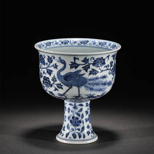 A BLUE AND WHITE PORCELAIN STEM-CUP/MING DYNASTY: A BLUE AND WHITE PORCELAIN STEM-CUP/MING DYNASTY 15.7 cm L x 17.9 cm H The upright sides painted in a vibrant underglaze blue with phoenix among peony scrolls.