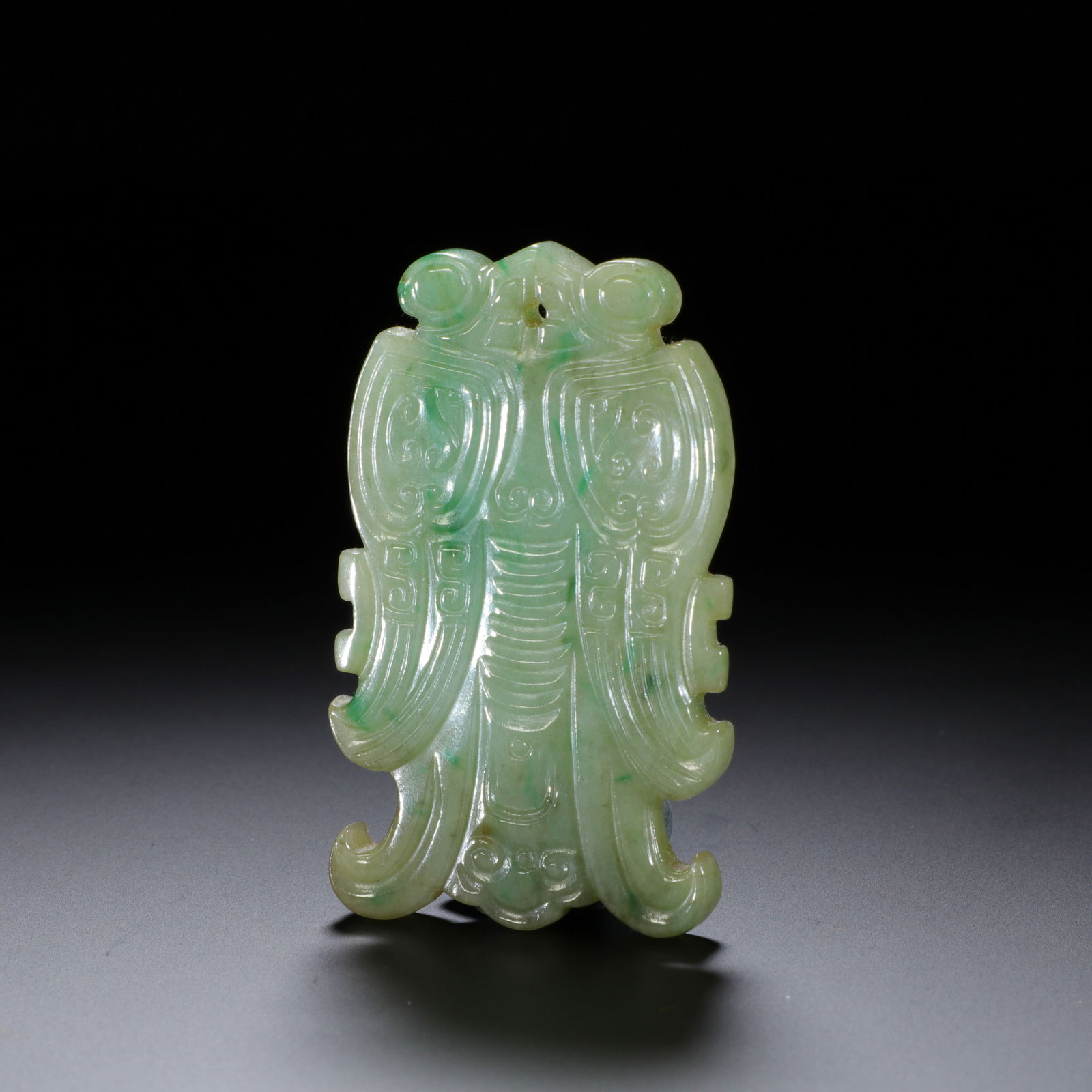 CHINESE JADEITE CICADA PENDANT: Dimensions: L. 5.3 cm. W. 3.2 cm. This striking Chinese jadeite cicada pendant measures 5.3 cm in length and 3.2 cm in width, carved from celadon jadeite with soft apple-green veining. The cicada is r