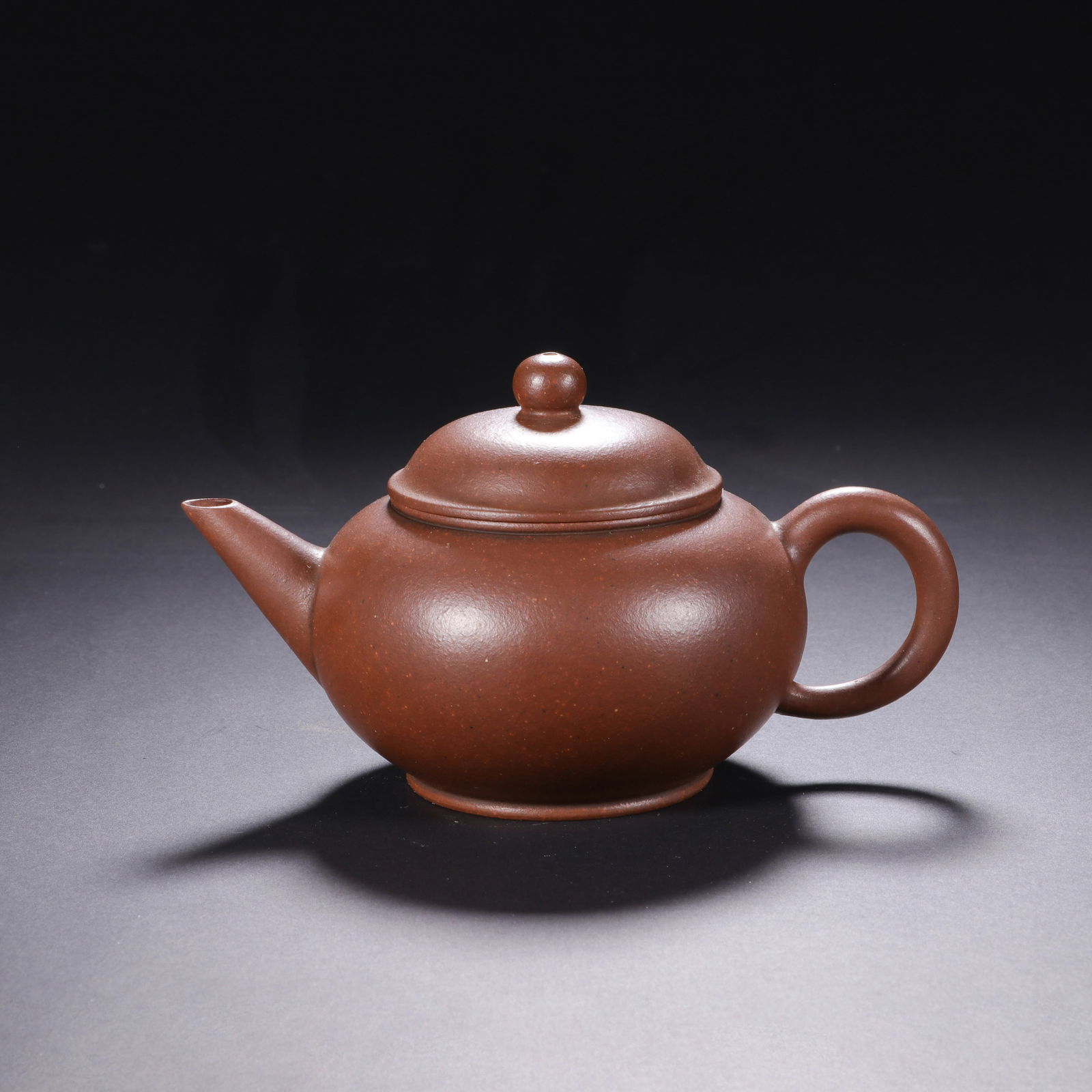 CHINESE YIXING CLAY TEAPOT: Dimensions: H. 7 cm. W. 12.5 cm. This elegant Chinese Yixing clay teapot measures 7 cm in height and 12.5 cm in width, crafted from rich reddish-brown Yixing clay with a fine, matte texture characteri