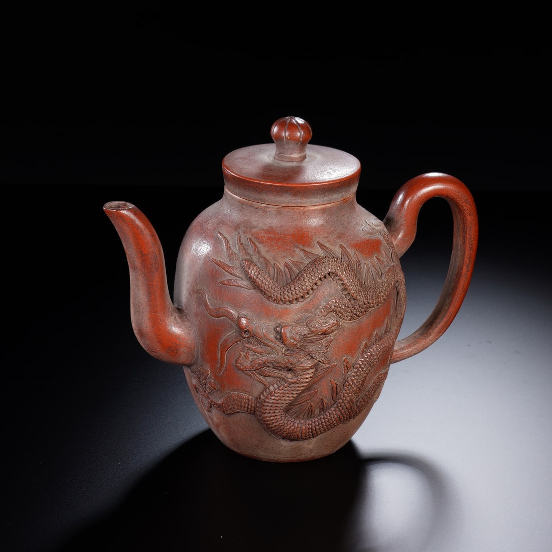 CHINESE YIXING ZISHA DRAGON TEAPOT: Dimensions: 15x9x12 cm. This distinctive Chinese Yixing zisha clay teapot features a bulbous body with bold relief carving of a sinuous dragon, its scaled body and expressive features rendered with st