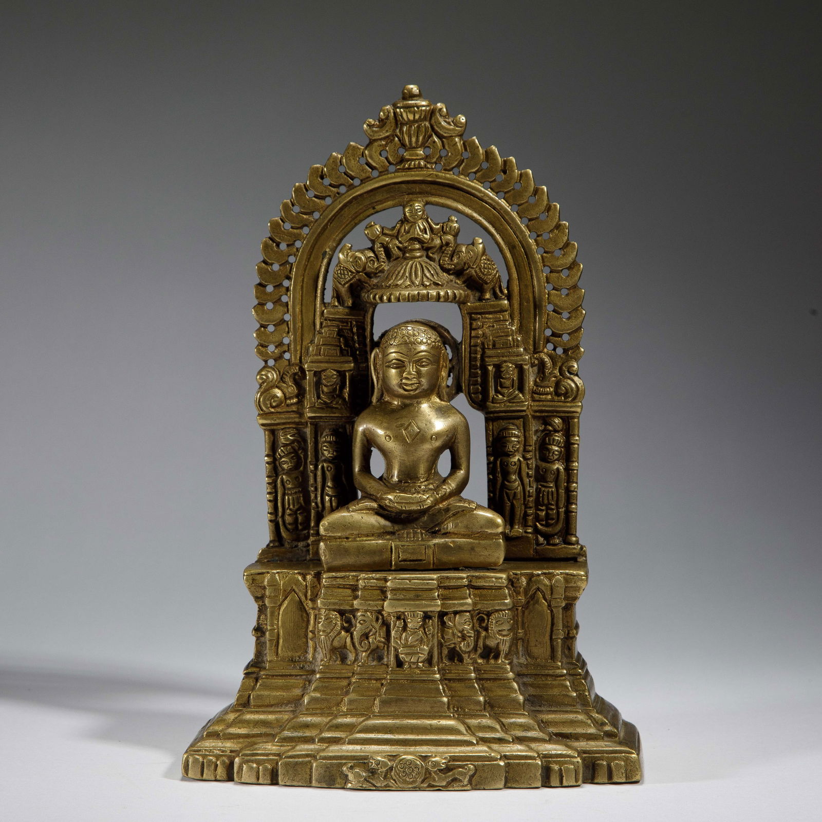 CHINESE GILT BRONZE GURU BUDDHA STATUE: Dimensions: L. 13.8 cm. W. 7 cm. H. 21 cm. Weight 1600 grams. This finely cast gilt bronze statue depicts a guru Buddha seated in meditative lotus pose, framed by an elaborate arched aureole