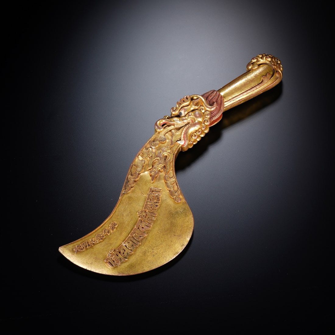 CHINESE GILT BRONZE VAJRA AXE: Dimensions: 28x8x2.5 cm. Weight 830 grams. This Chinese gilt bronze vajra axe (yue dao) features a dragon-carved handle junction, incised Tibetan Sanskrit inscriptions on the blade, and a polished gil